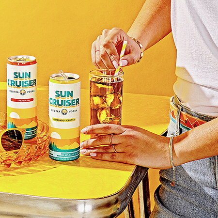 Multiple flavors of Sun Cruiser on a table while a man stirs a glass