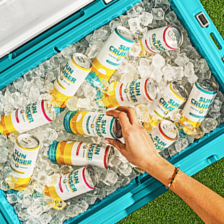 A hand reaching in to grab a can of Sun Cruiser out of a cooler